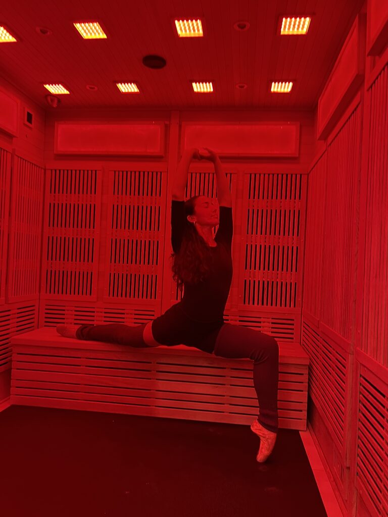A woman stretches in a gemstone-lined infrared sauna room.